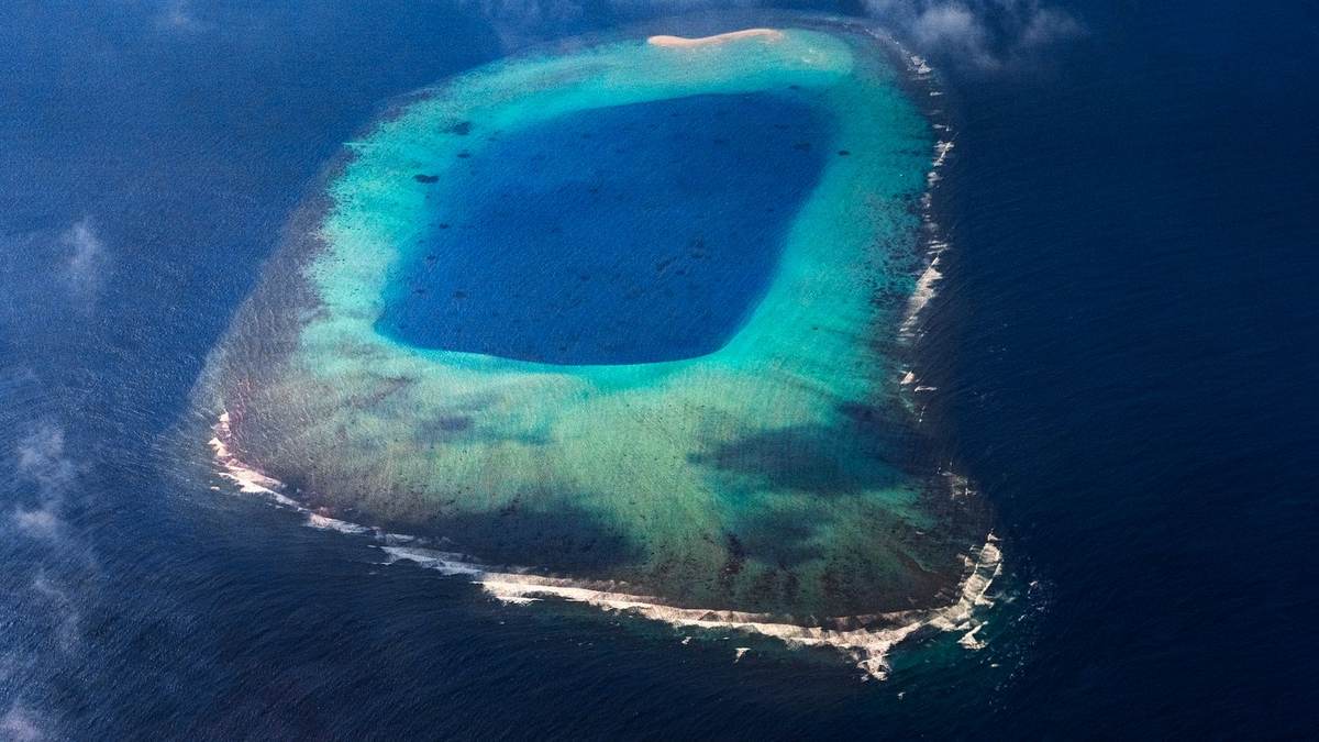 Aerial view of a turquoise Mauritian lagoon with a single boat at anchor