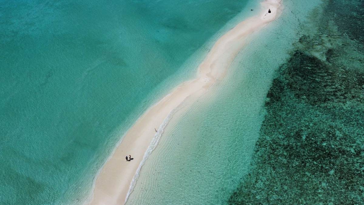 Dinner table laid on a white sandbank in a Mauritian lagoon at dusk